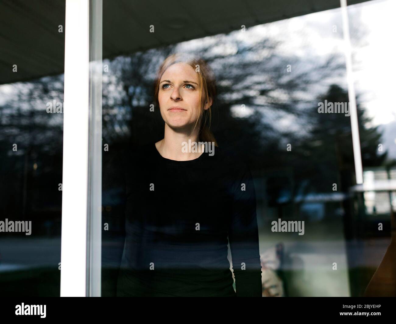 Woman looking through window Stock Photo