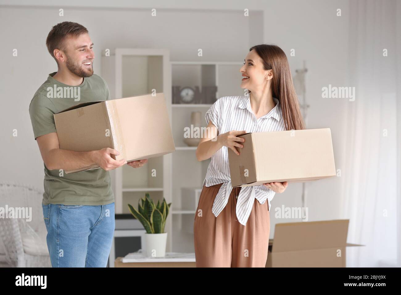 Happy young couple with moving boxes in their new house Stock Photo - Alamy