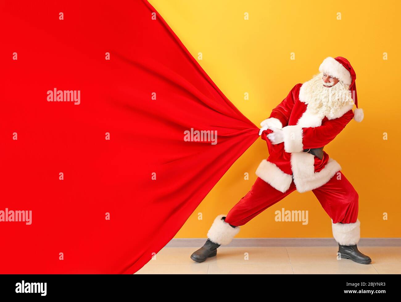 Portrait of Santa Claus pulling big bag against color wall Stock Photo ...