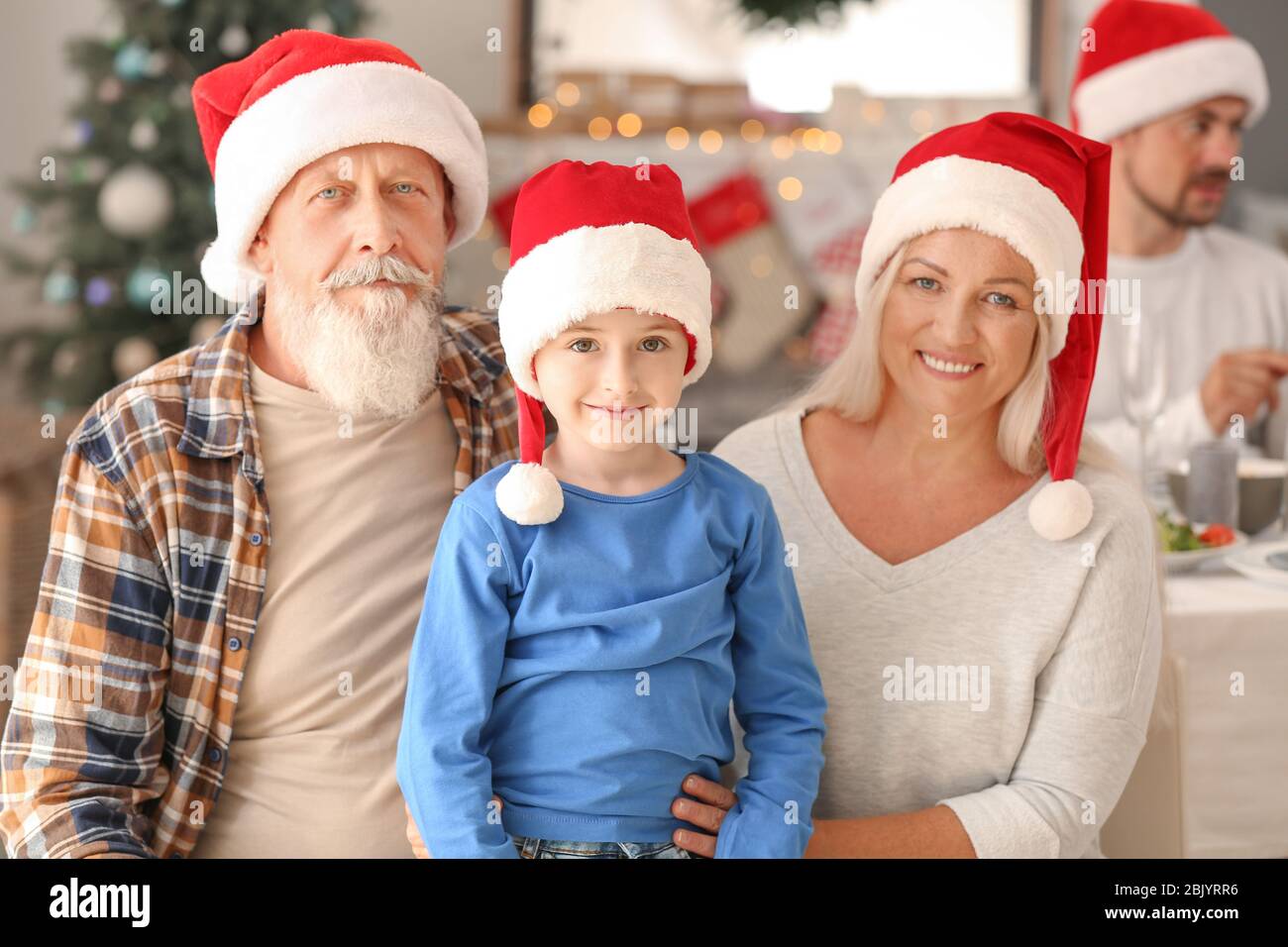 Happy Grandparents With Little Boy During Christmas Party At Home Stock