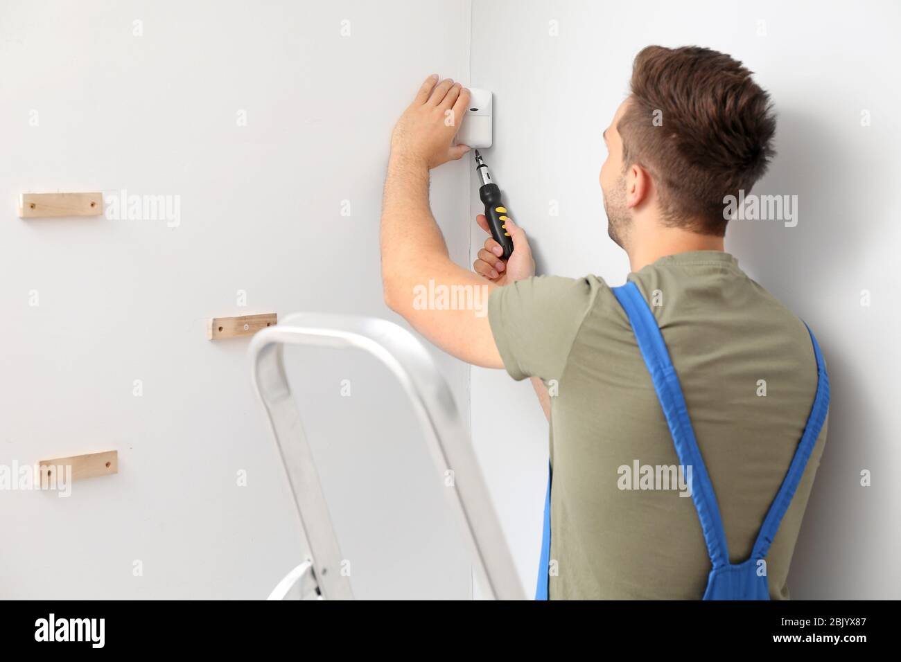 Electrician installing alarm system indoors Stock Photo