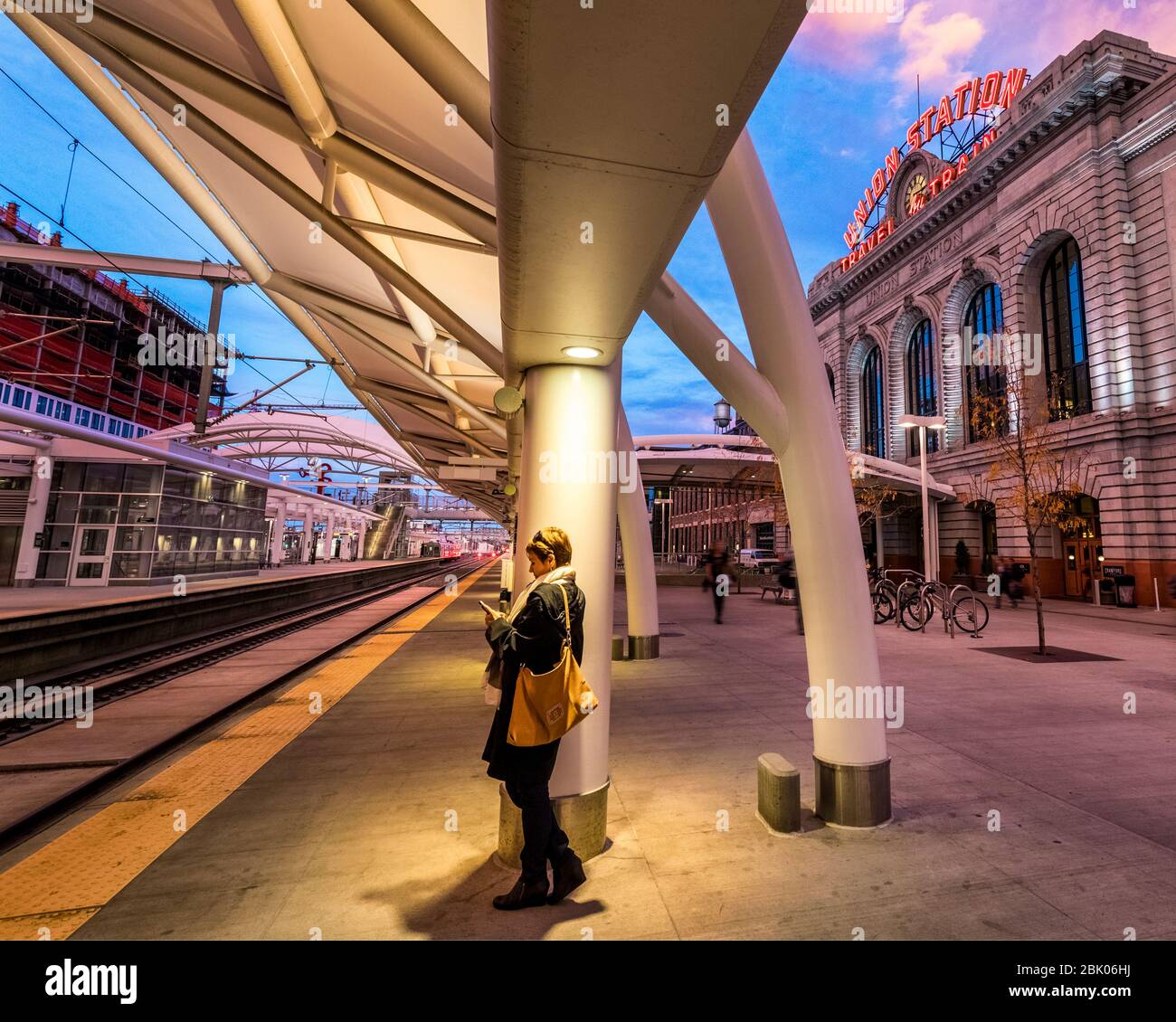 A commuter checks her phone while waithing for a light rail train at Union Station, Denver, Colorado, USA. Stock Photo