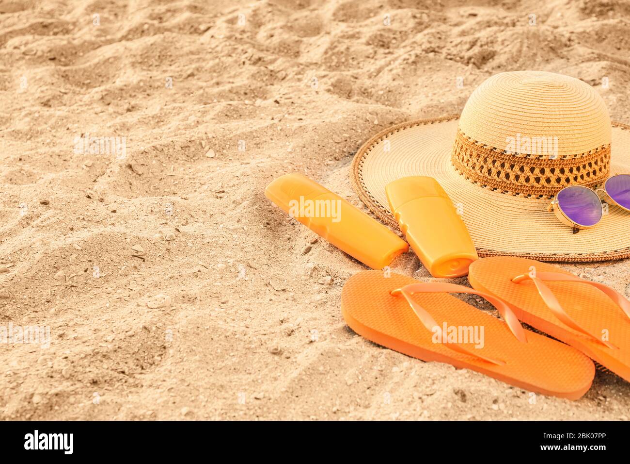 Hat with sunscreen cream, flip-flops and sunglasses on sand beach Stock ...
