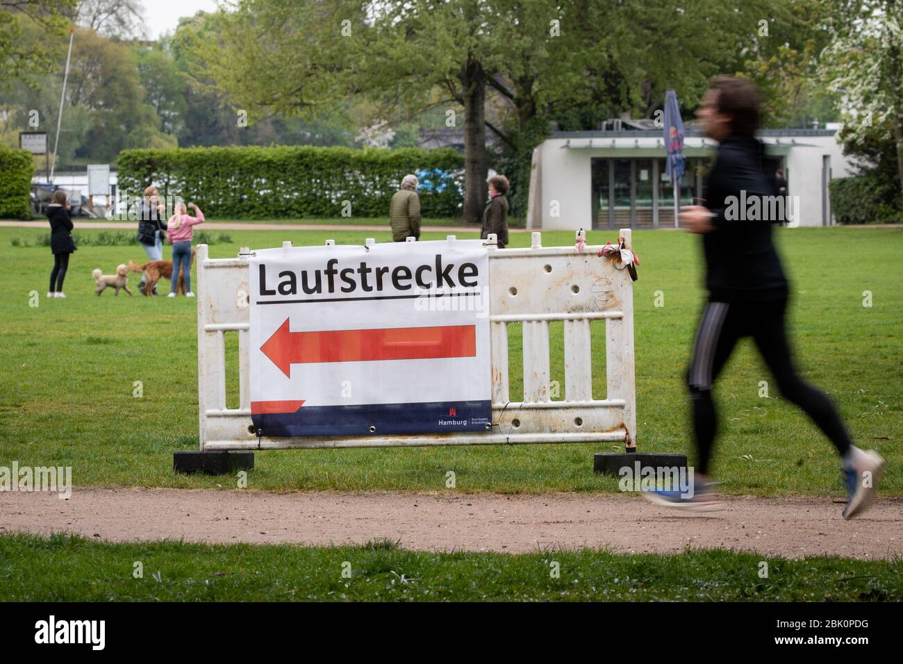 Hamburg, Germany. 30th Apr, 2020. A jogger runs on a footpath along the Außenalster past a sign of the Eimsbüttel district office with the inscription: 'Laufstrecke'. In view of the corona pandemic, Hamburg's citizens should continue to show consideration in the open air and maintain a distance of at least 1.5 metres between them. Credit: Christian Charisius/dpa/Alamy Live News Stock Photo