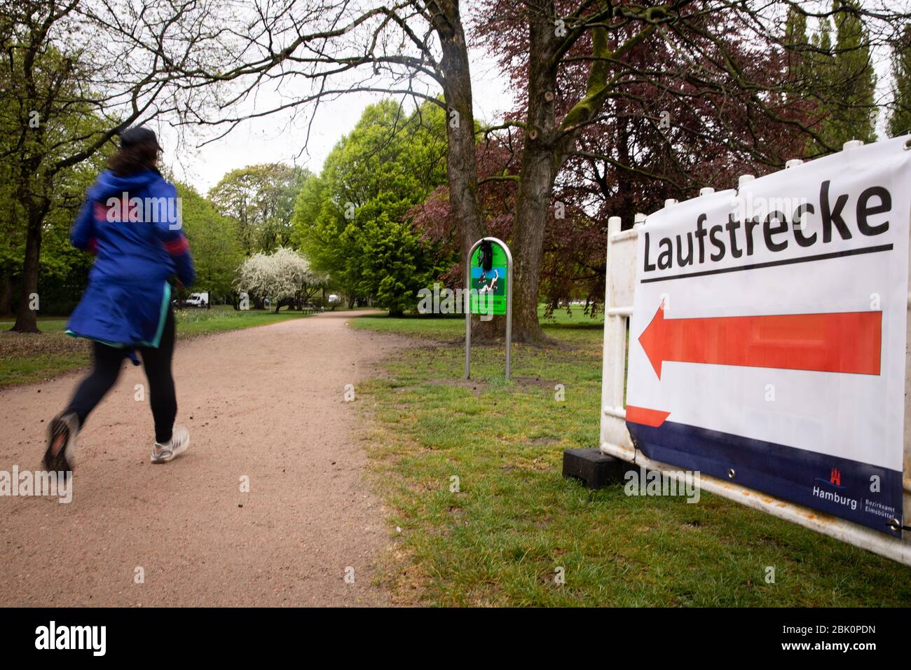 Hamburg, Germany. 30th Apr, 2020. A jogger runs on a footpath along the Außenalster past a sign of the Eimsbüttel district office with the inscription: 'Laufstrecke'. In view of the corona pandemic, Hamburg's citizens should continue to show consideration in the open air and maintain a distance of at least 1.5 metres between them. Credit: Christian Charisius/dpa/Alamy Live News Stock Photo