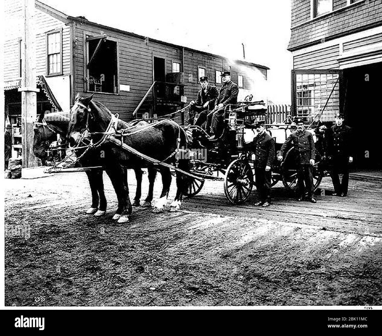 Horse-drawn hose cart and fire fighters in front of Madison St Firehouse -5 Seattle (CURTIS 1479). Stock Photo