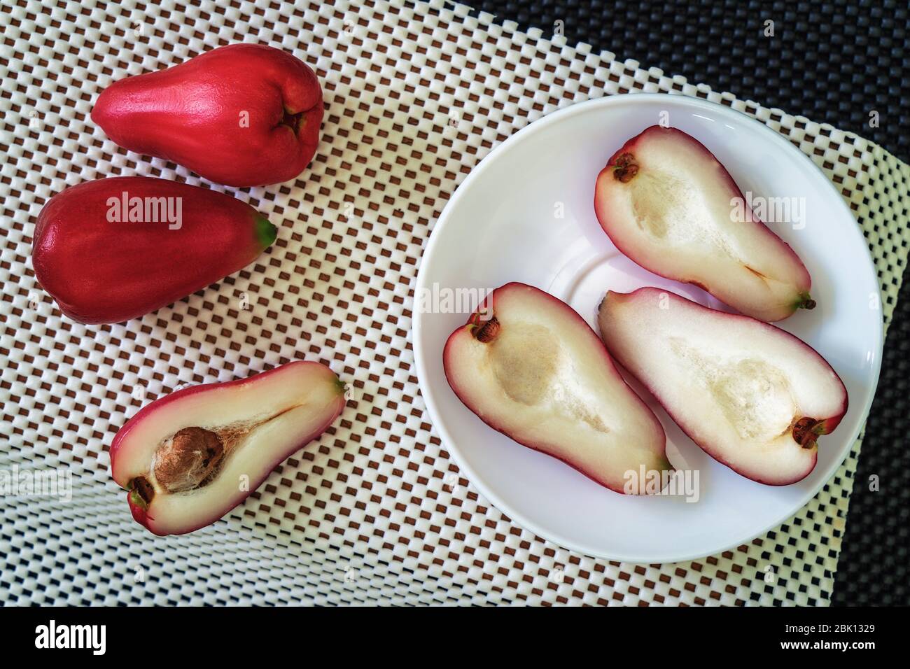 three halves of pomarosa fruit in a plate on a white surface and more fruits aside Stock Photo Alamy