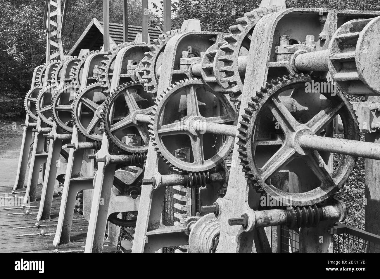 Gear wheels, toothed belts, chains, shafts and racks at a weir on the river Aller, Germany, black and white Stock Photo