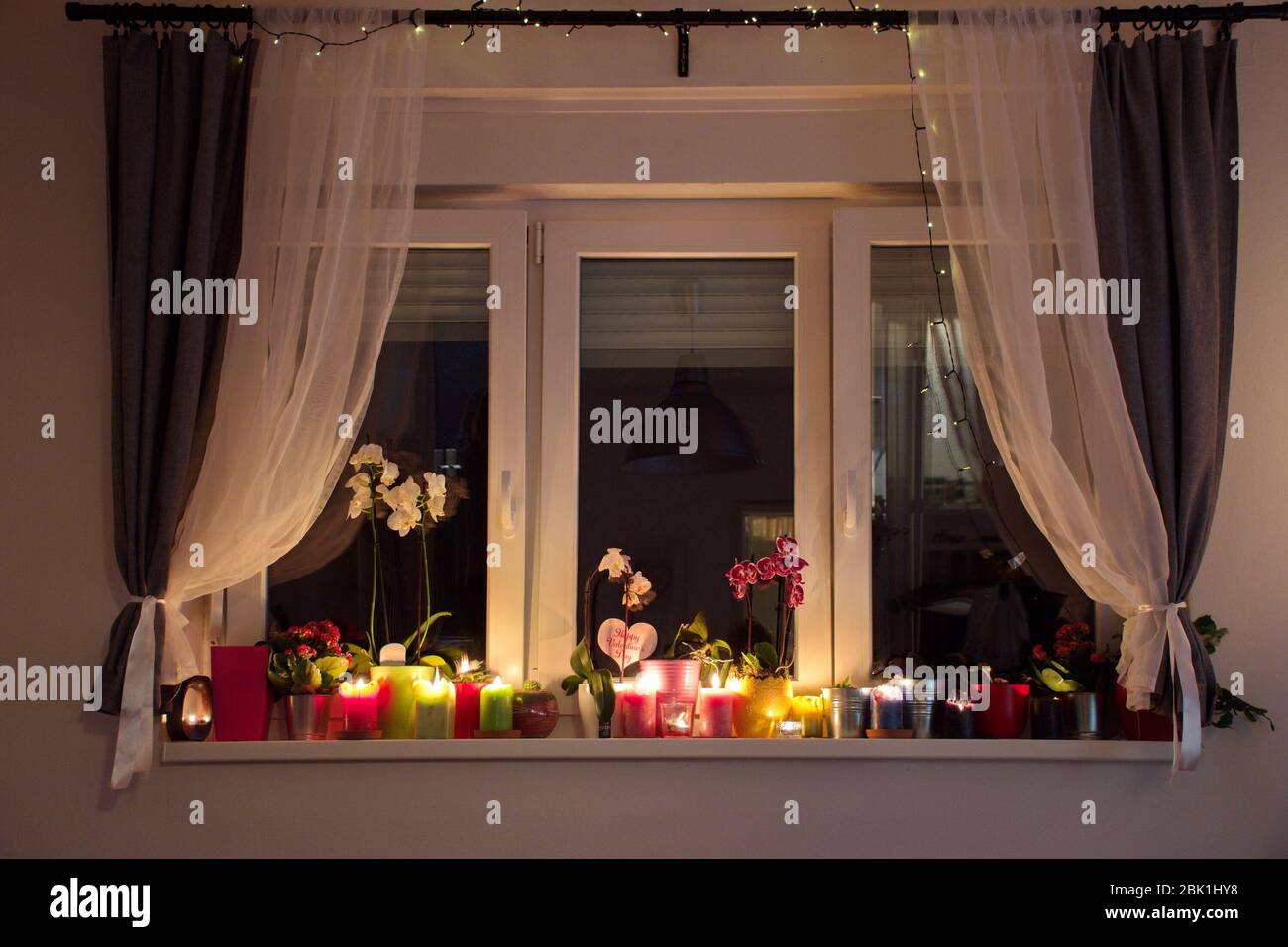 Window decorated with candles and potted plants Stock Photo