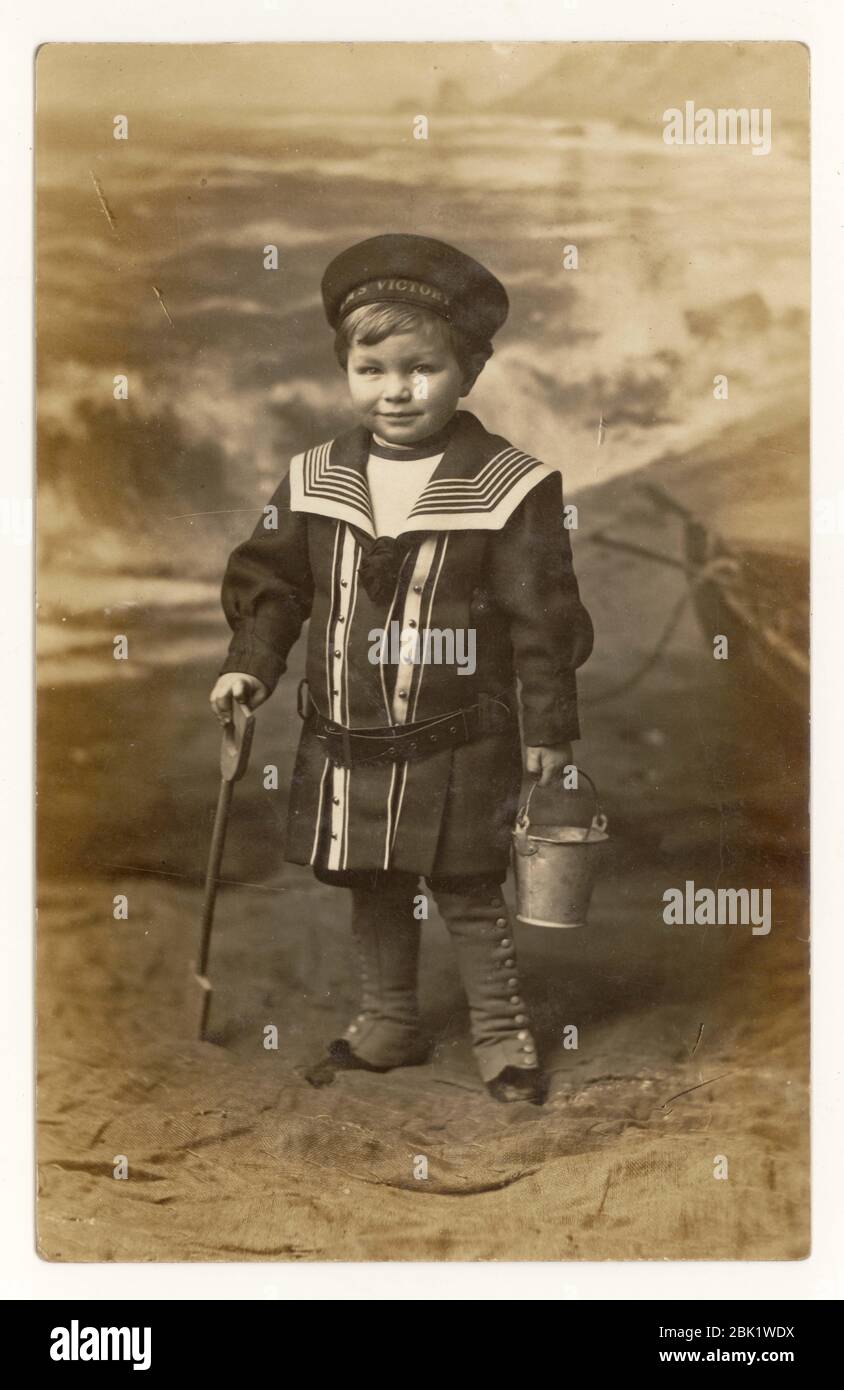 Early 1900's seaside postcard of young boy wearing an HMS Victory cap, sailor suit, Eastbourne, Sussex, England, U.K.   circa 1908 Stock Photo