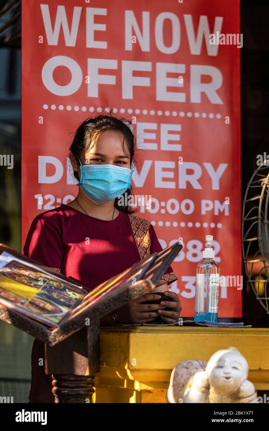 Thai waitress with face mask at restaurant waiting for take away customers at restaurant during Covid 19 pandemic, Bangkok, Thailand Stock Photo