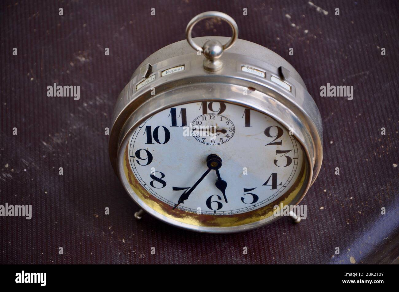 Ancient alarm clock on vintage brown suitcase. Alarm clock, ready to stend up. Stock Photo