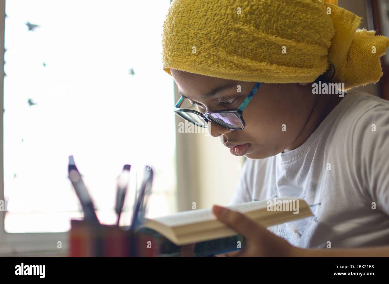 Cute little school girl studying at home during lock down period due to Corona Virus pandemic. Stock Photo