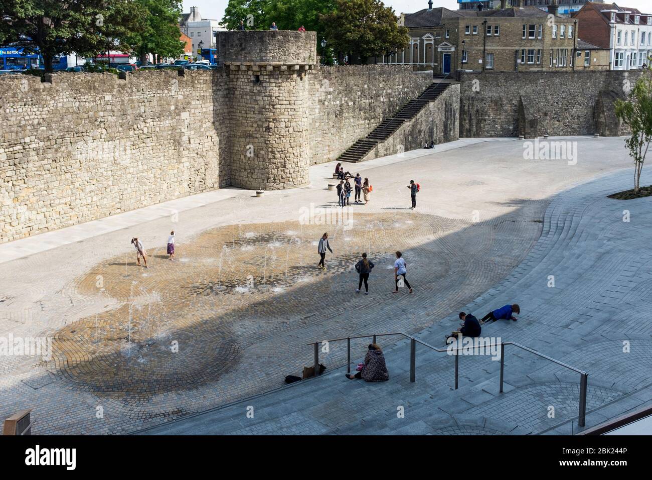 People enjoying warm weather in open space by Old Town Wall, Southampton, Hampshire, UK Stock Photo