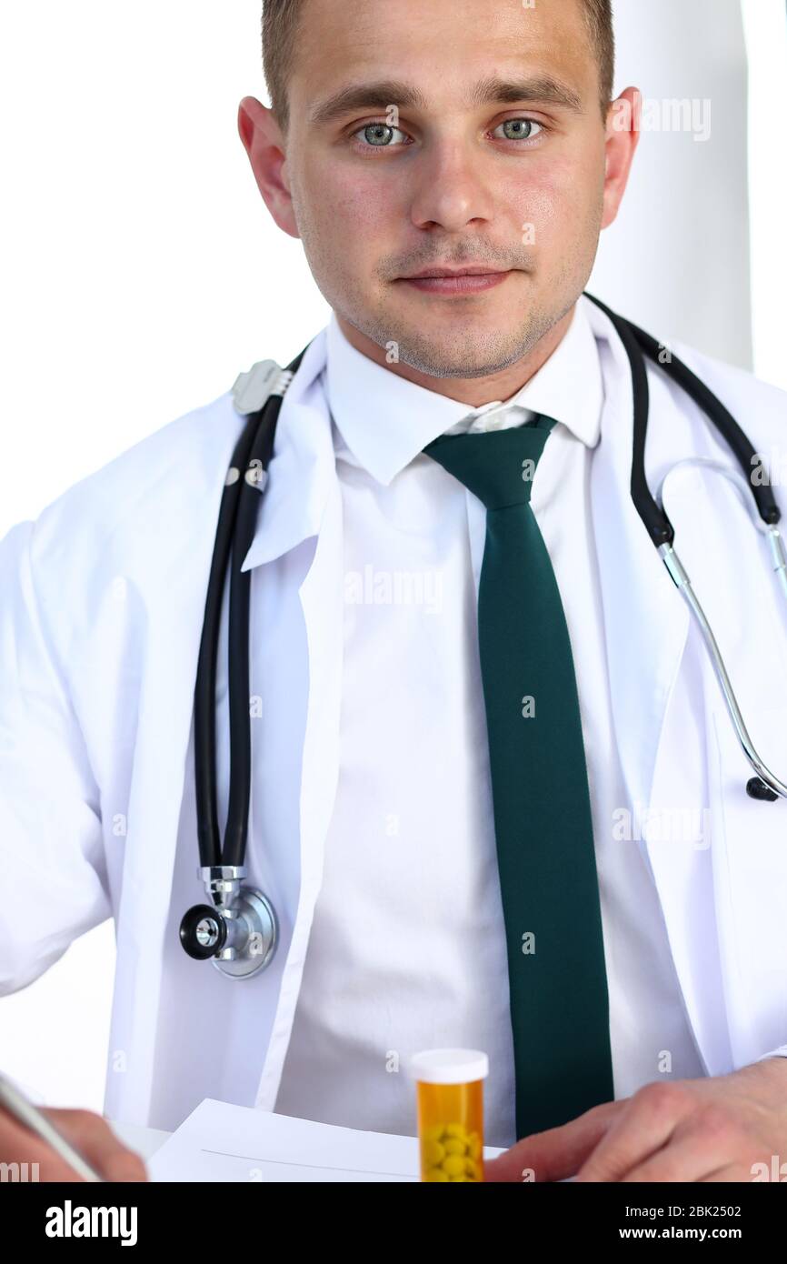 Handsome smiling male doctor write prescription at workplace Stock ...