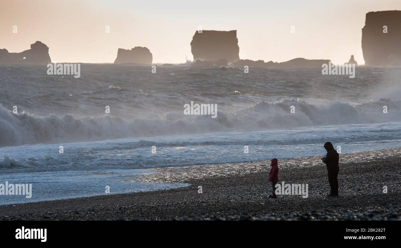 Unrecognised people enjoying the beautiful reynisfjara beach with stormy Atlantic waves ,at Vik I Mydral in Iceland Stock Photo