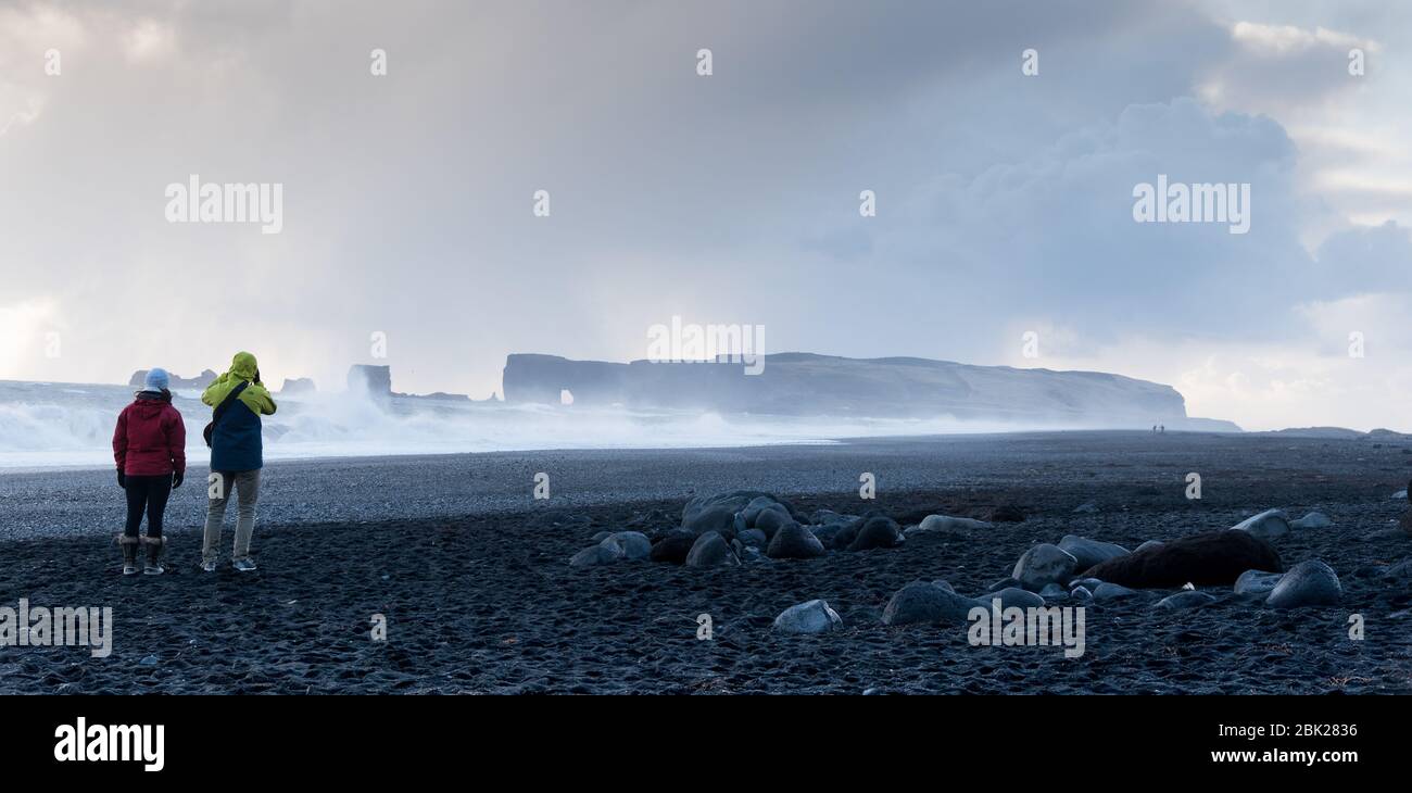 Unrecognised people enjoying the beautiful reynisfjara beach with stormy Atlantic waves ,at Vik I Mydral in Iceland Stock Photo