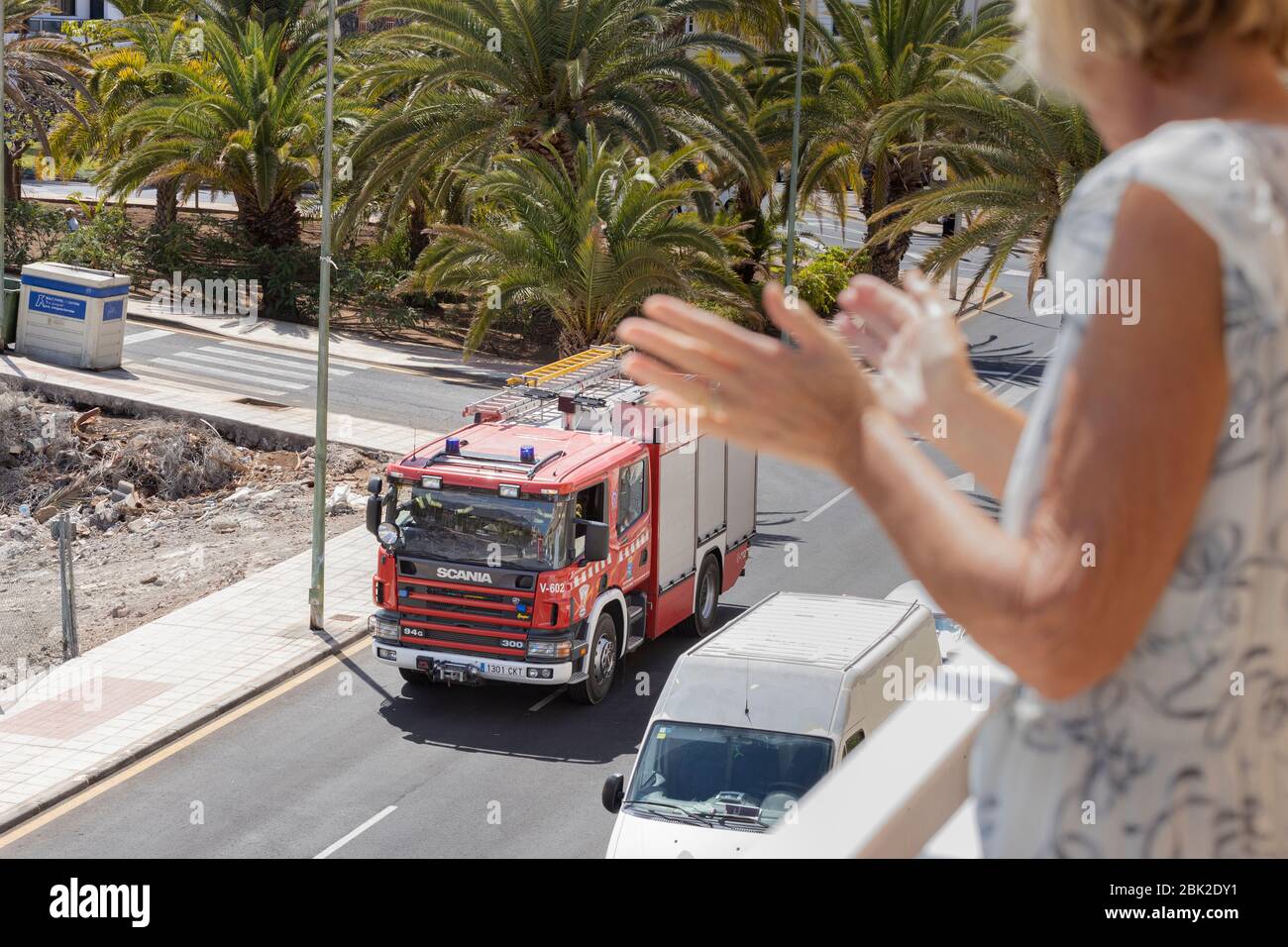 Clapping volunteer firemen driving through the village with sirens and lights flashing, state of emergency, Playa San Juan, Tenerife, Canary Islands Stock Photo