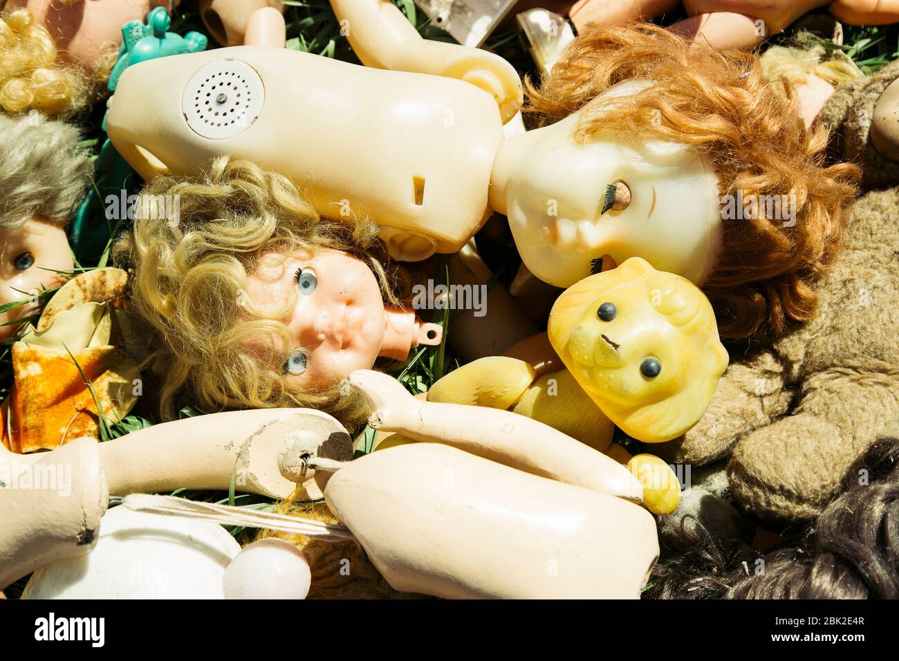 Many old broken dolls and toys on the grass thrown like a garbage Stock