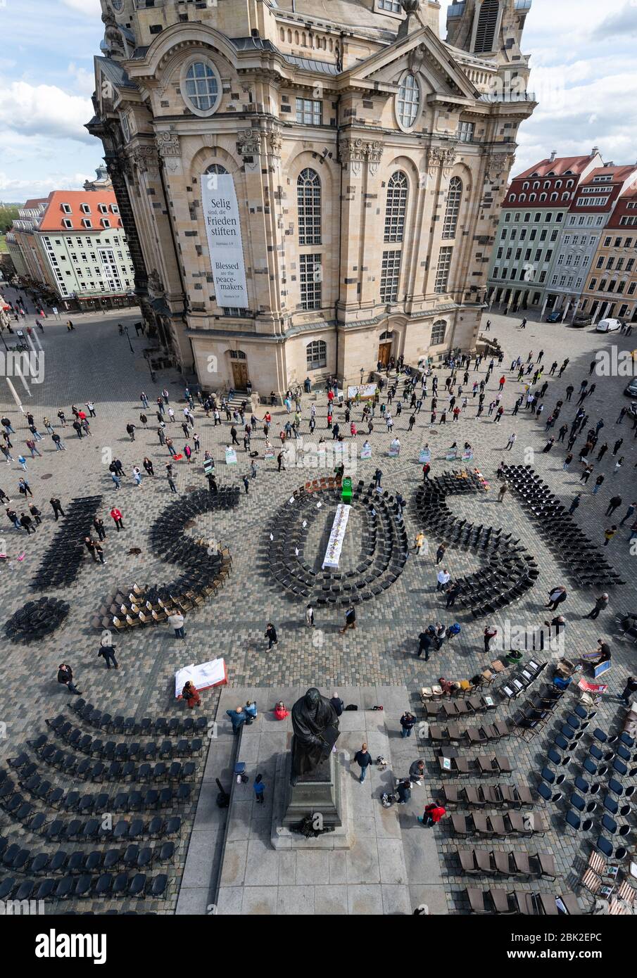 Dresden, Germany. 01st May, 2020. The letters 'SOS' formed with chairs stand on the Neumarkt between the Frauenkirche and the monument of Martin Luther during an action with which the Saxon gastronomy, hotel and event industry wants to draw attention to their problems caused by the effects of the Coronavisus pandemic. In front of hundreds of empty chairs and tables in front of the Frauenkirche, a letter with demands for the preservation of the industries was handed over to the Minister for Culture and Tourism in Saxony. Credit: Robert Michael/dpa-Zentralbild/dpa/Alamy Live News Stock Photo