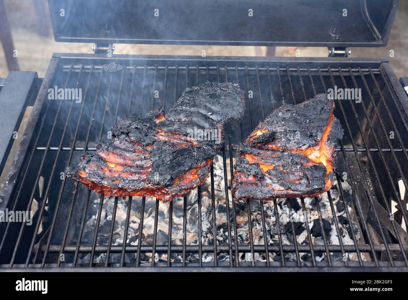 overcooked ruined black bbq ribs on the charcoal grill . Stock Photo