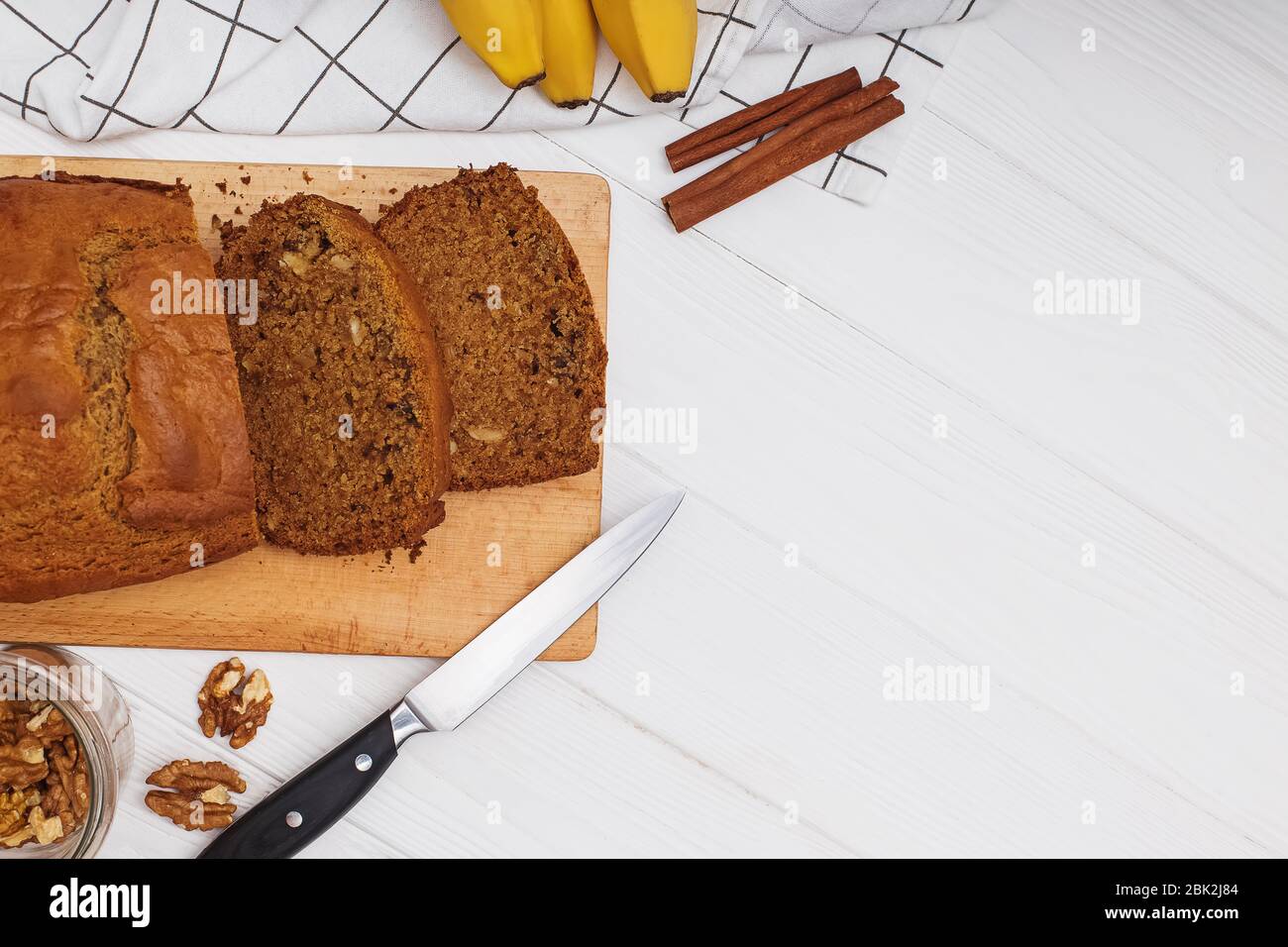 Freshly baked delicious homemade banana bread with walnuts on white wooden table . Flat lay with copy space Stock Photo