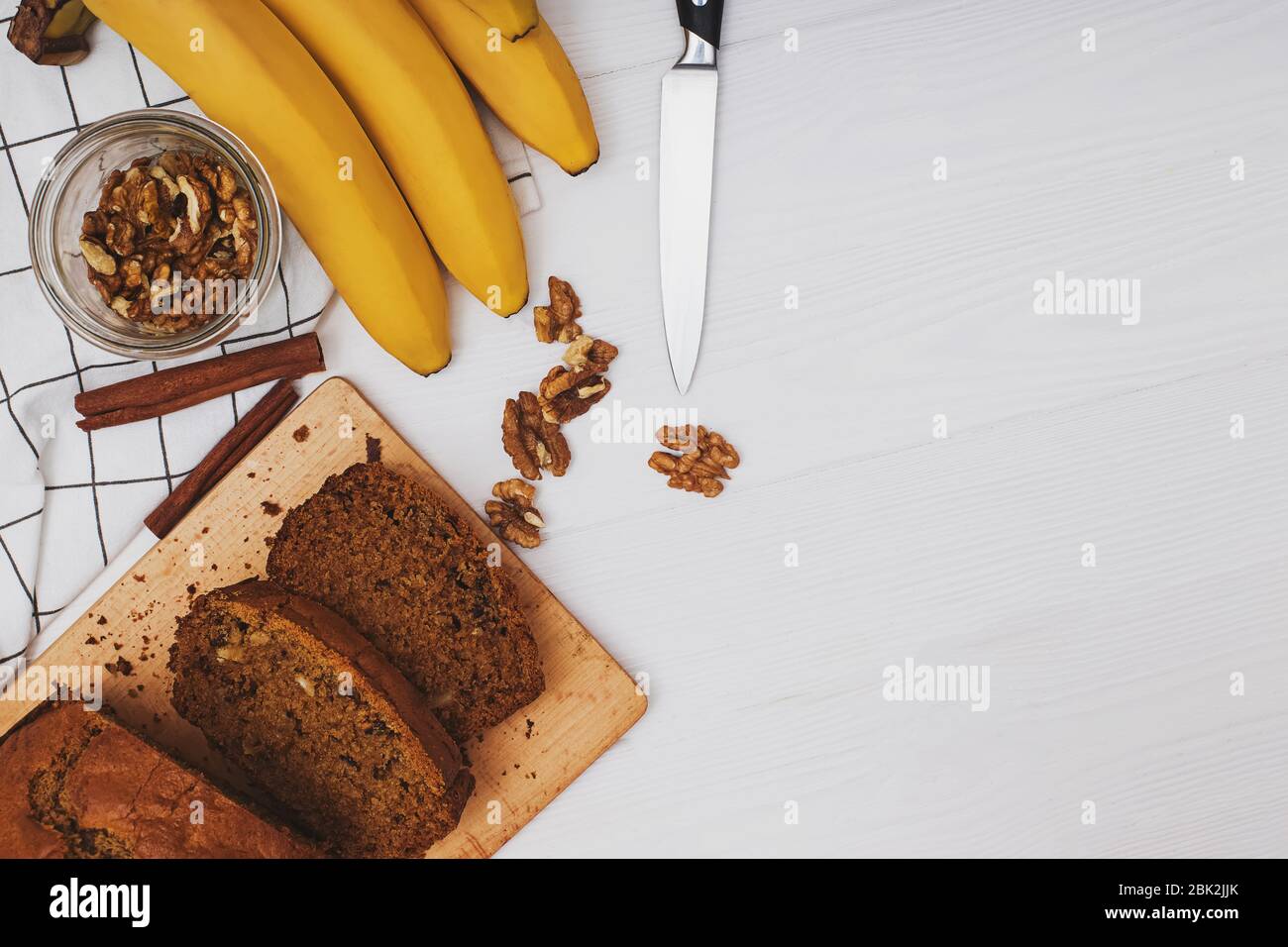 Freshly baked delicious homemade banana bread with walnuts on white wooden table . Flat lay with copy space Stock Photo