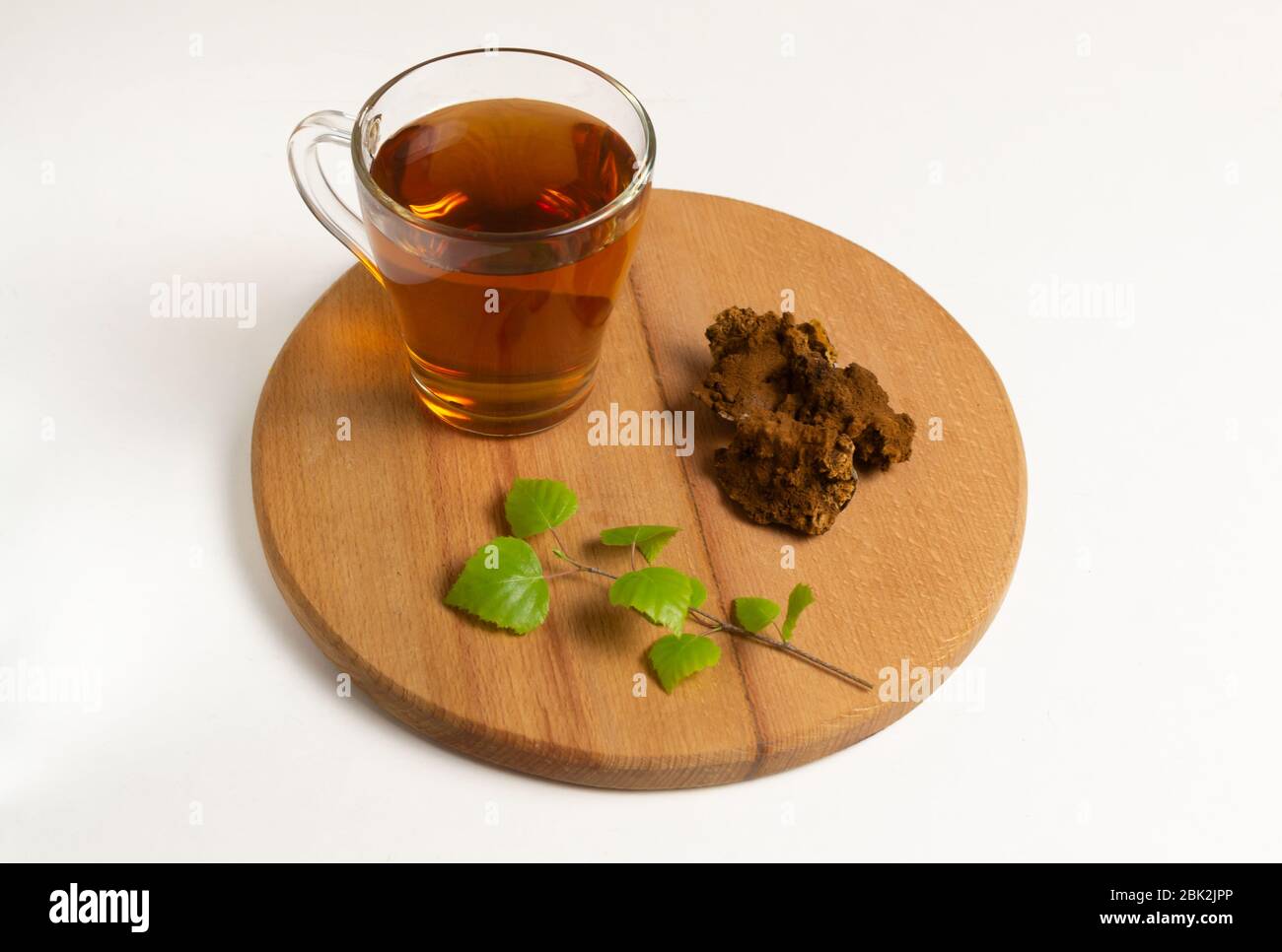 A cup of tea chaga with mushroom and a birch branch on a round wooden board. Stock Photo