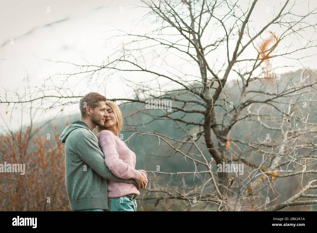 Couple In Love Stands Against Nature And Hugging Tenderly Stock Photo