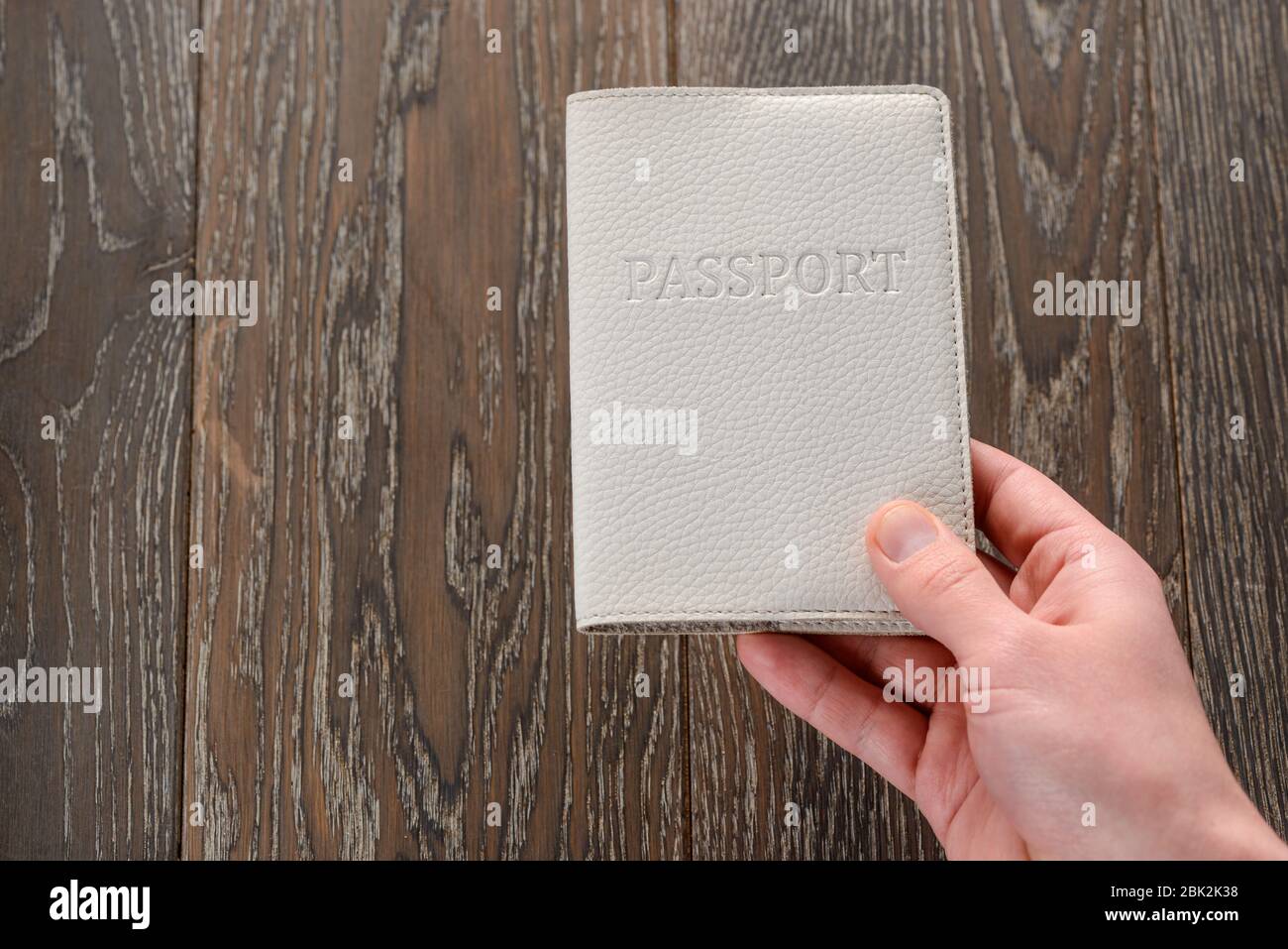 Hand holding a passport on wooden background Stock Photo - Alamy