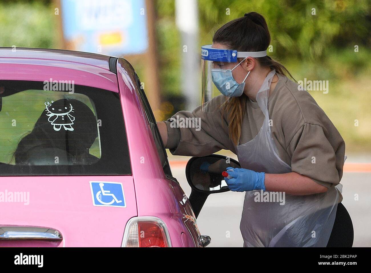 A medical worker takes a swab at a drive-thru coronavirus testing station in the car park of Chessington World of Adventures Resort in southwest London. Stock Photo