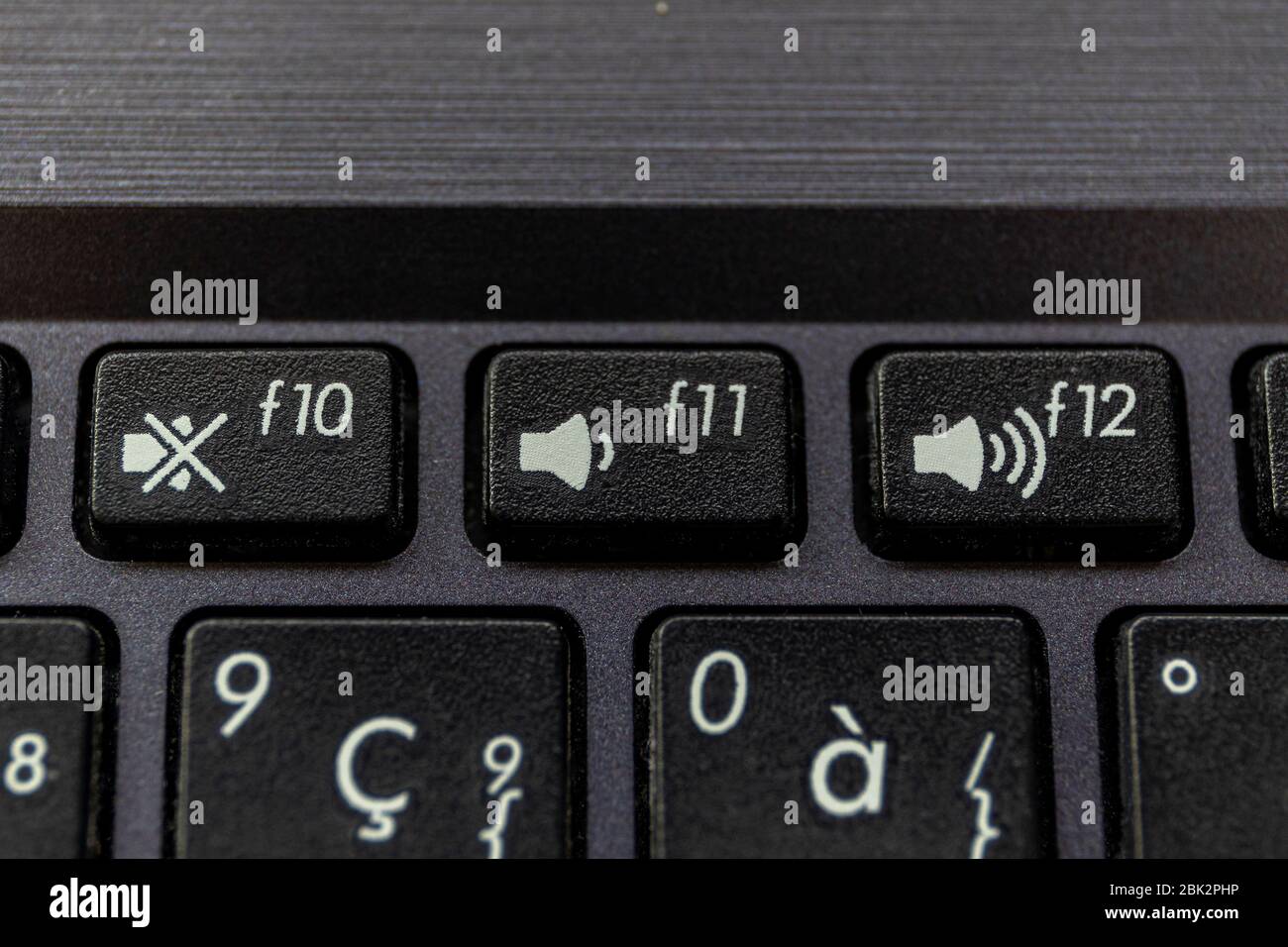 A close up portrait of the mute, volume up and volume down buttons on a laptop keyboard. The physical keys are black with a white icon on them to disp Stock Photo