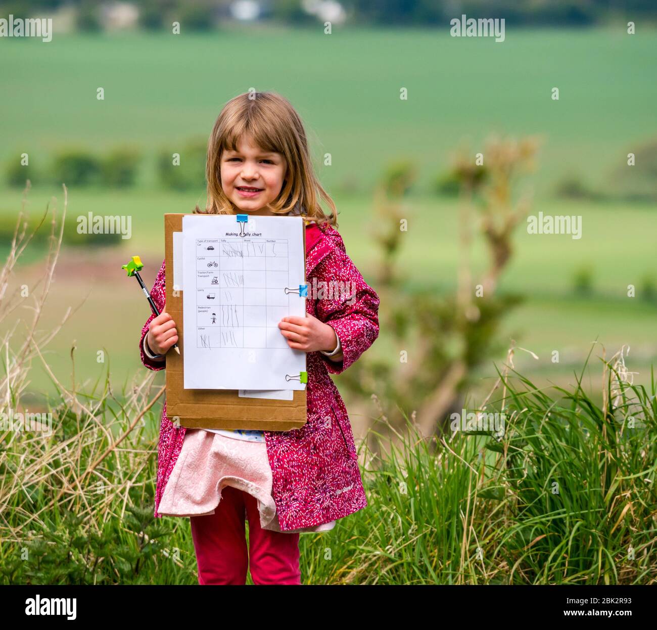 East Lothian, Scotland, United Kingdom. 1st May, 2020. Home schooling: Alice, aged 5 years is a Primary 1 school pupil. She works on an outdoor numeracy task at the roadside learning how to tally, counting cars, cyclists, pedestrians, tractors and lorries Stock Photo