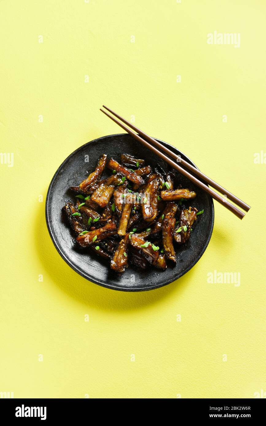 Stirfry Bulgogi Eggplant on plate over yellow background with freee text space. Fried aubergine