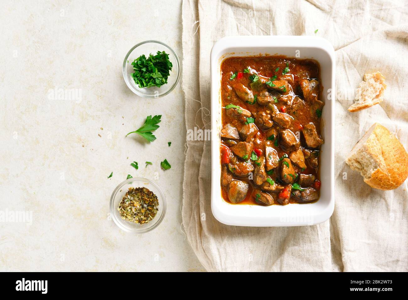 Cooked chicken livers in baking dish over light stone background with