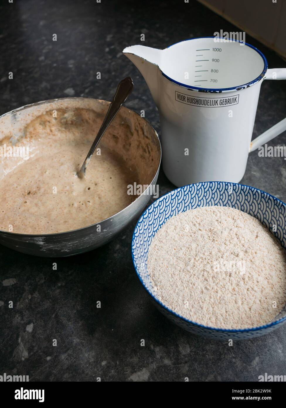 A sourdough starter with measuring jug and bowl of flour, ready to
