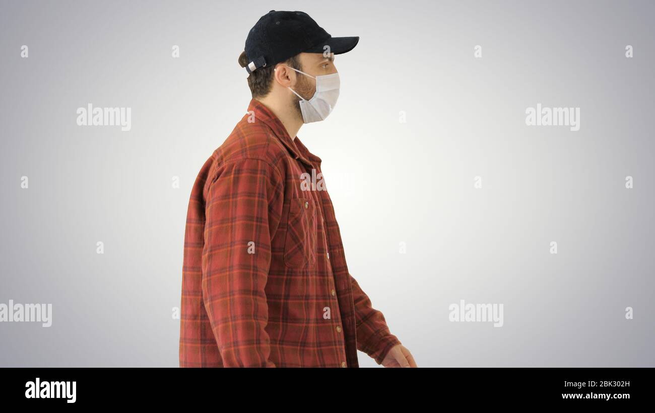 American farmer in a cap and medical mask walks along on gradient background. Stock Photo