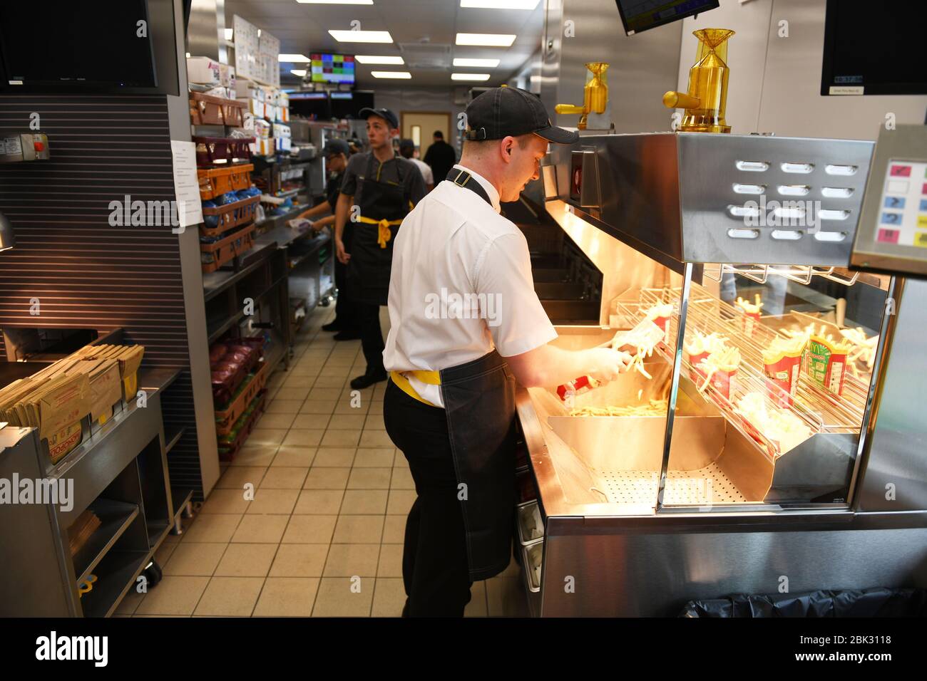 A member fo staff serves fries into a carton at a McDonalds restaurant