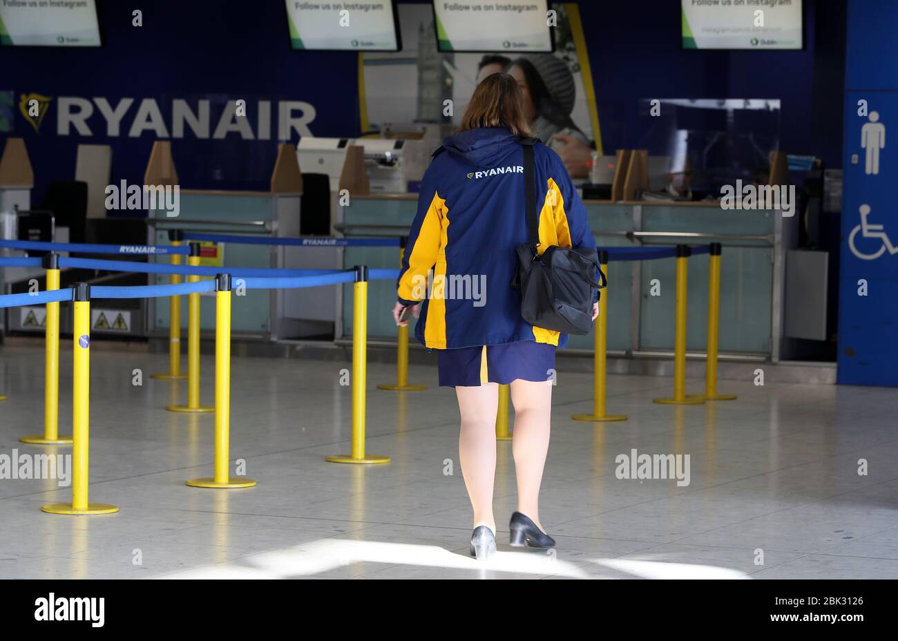A woman approaches a Ryanair check in desk in terminal one at Dublin airport. The budget airline group has announced that up to 3,000 jobs across pilots and cabin crew will be cut in a restructuring programme that could also involve unpaid leave, pay slashed by up to 20%, and the closure of 'a number of aircraft bases across Europe' until demand for air travel recovers. Picture date: Friday May 1, 2020. See PA story HEALTH Coronavirus. Photo credit should read: Brian Lawless/PA Wire Stock Photo