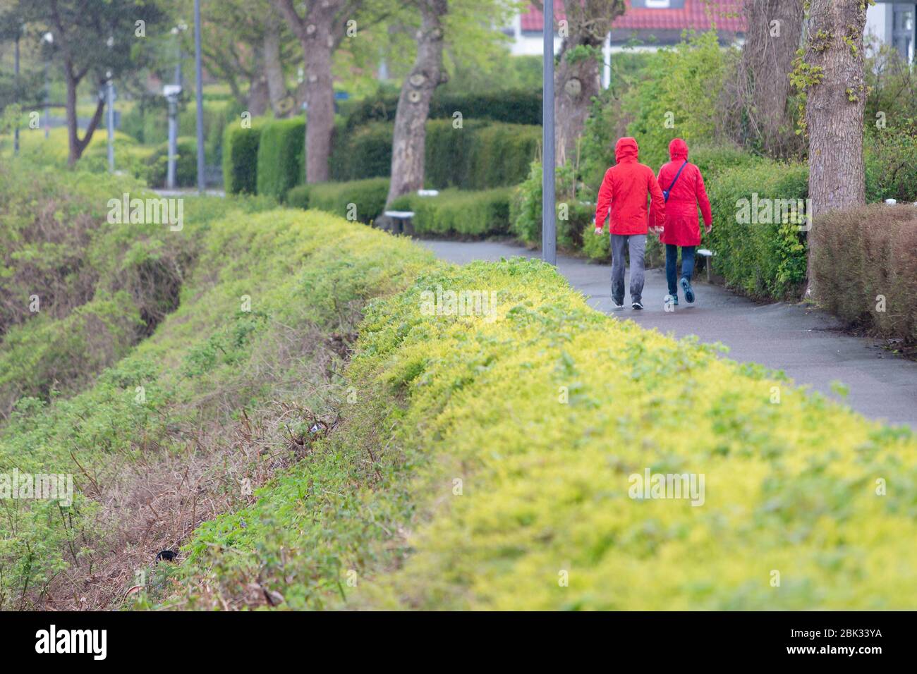 Kiel, Germany. 01st May, 2020. Two people are walking along a promenade in rain with rainwear. Sun and rain alternated on May 1 in Schleswig-Holstein. Credit: Frank Molter/dpa/Alamy Live News Stock Photo