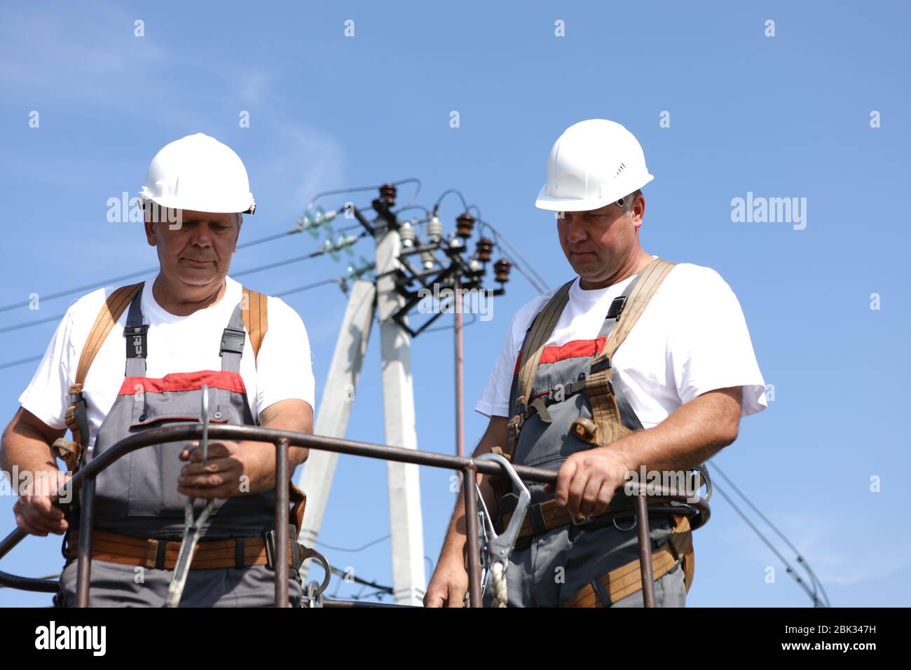 Two electrical workers on a lift. Engineers rise on a crane to repair a