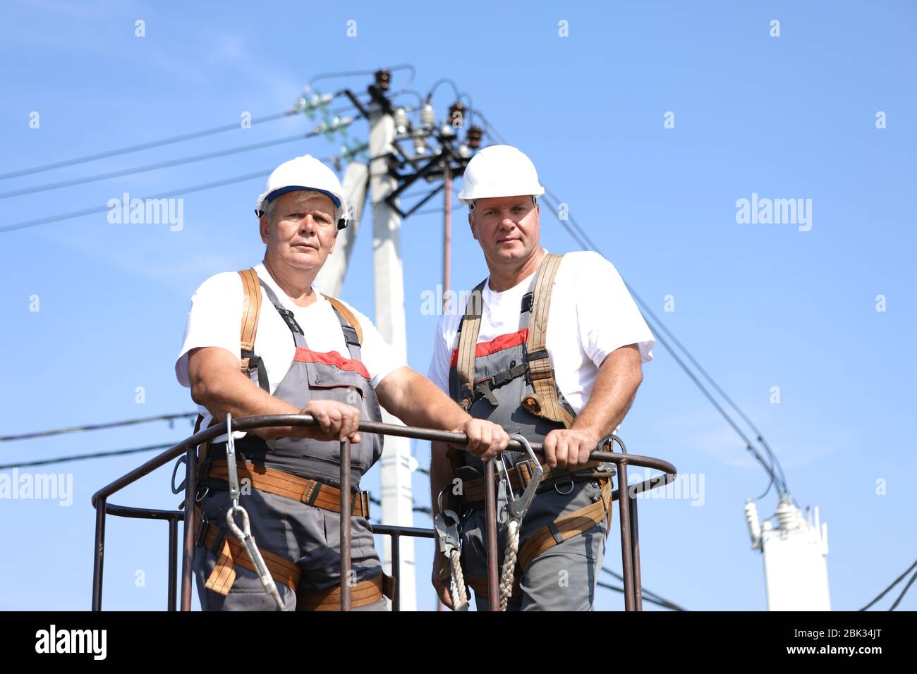 Two electrical workers on a lift. Engineers rise on a crane to repair a