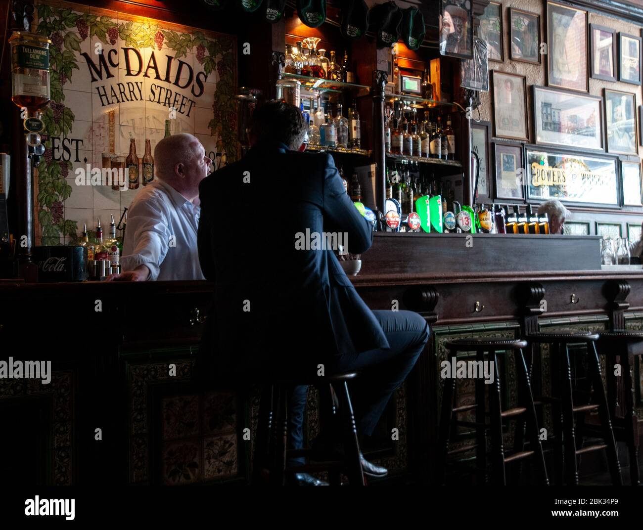 Publican and customer in conversation at the bar in McDaids pub in Harry Street in Dublin, Ireland. Stock Photo