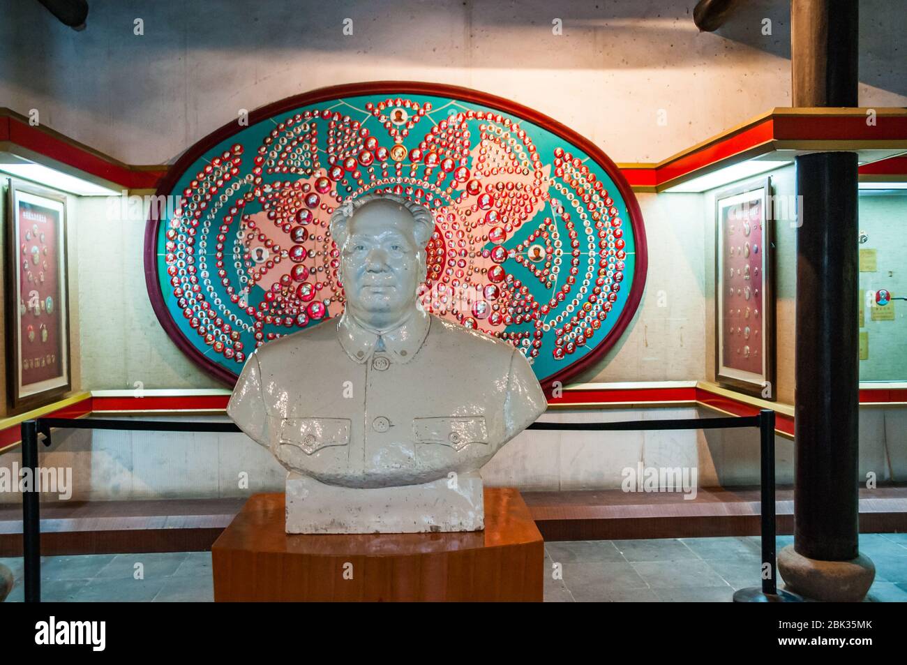 A Mao bust in front of a collection of Cultural Revolution era Mao badges at the Mao Zedong Images Badges Museum in Fengjing watertown on the outskirt Stock Photo