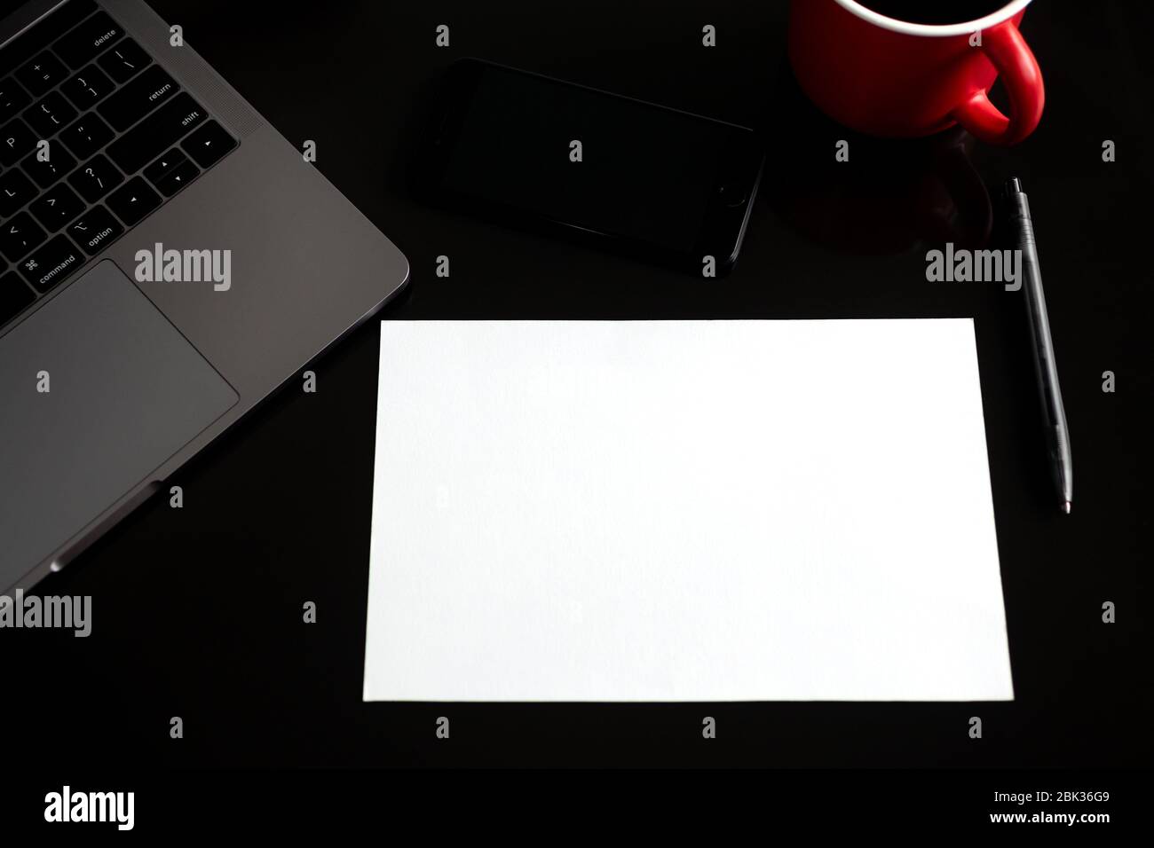 Toronto, Canada - 30, April, 2020: Blank paper with copy space, coffee cup, phone, laptop on black desk table. Top view, flat lay Stock Photo