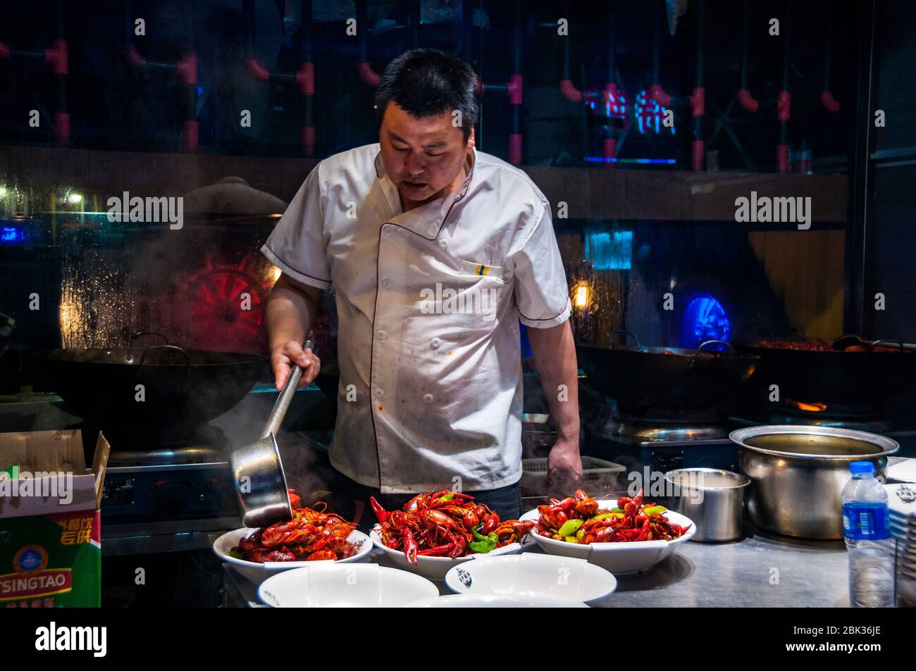 A chef plates up bowls of freshly fried crayfish (yabbies) on Shanghai's Shouning Road food street. Stock Photo