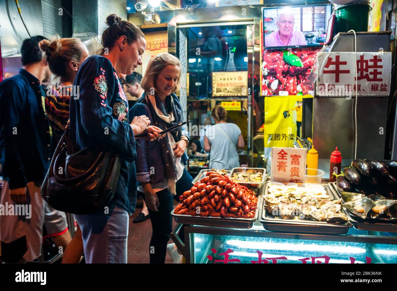 Tourists inspect the crayfish (yabbies) and other food outside a restaurant on Shanghai's Shouning Road. Stock Photo