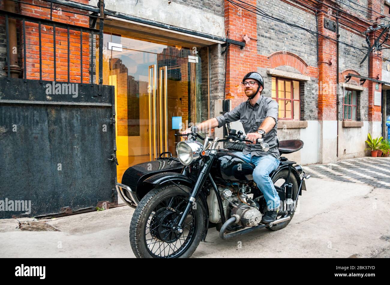 Shanghai Insider Arthur Humeau on his Changjiang 750 motorcycle sidecar in front of ArtCN, in the former Foh Sing flour mill building, on Shanghai Ins Stock Photo