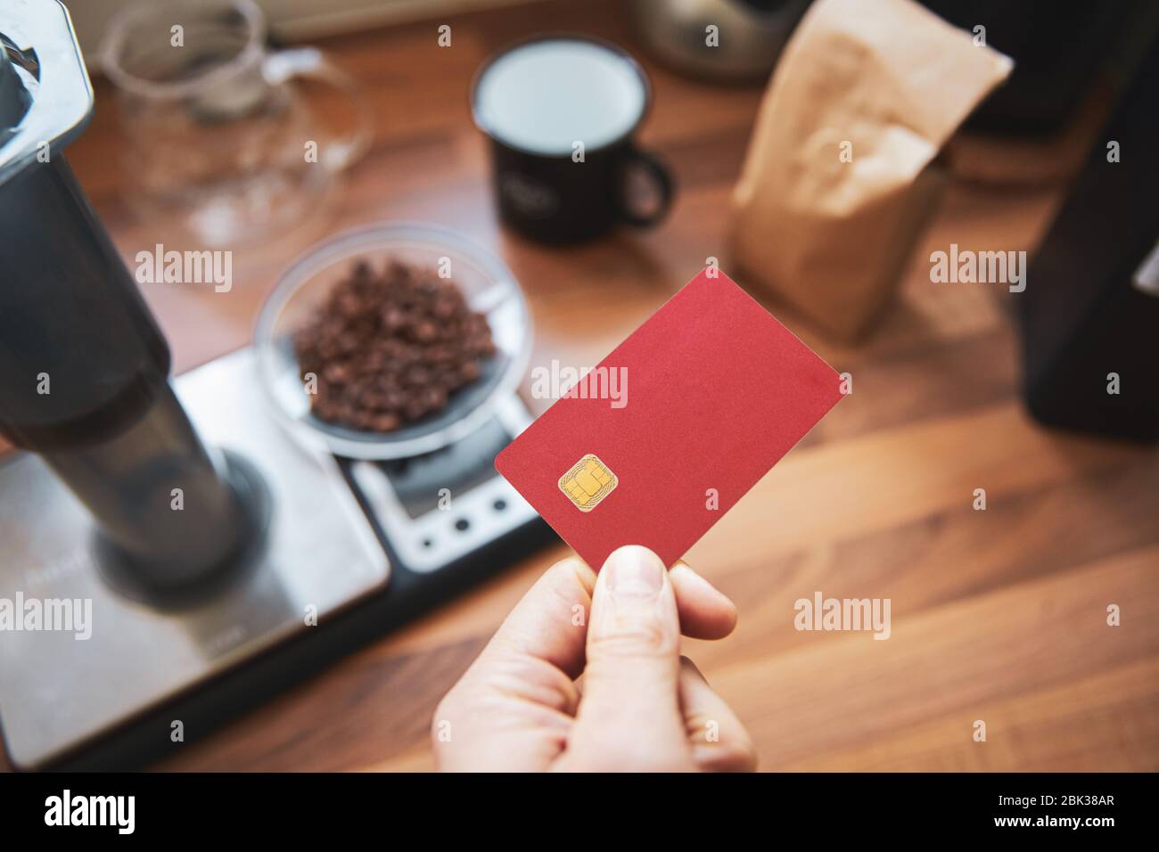 Man holding blank red debit card a coffee shop paying for a take out. Stock Photo