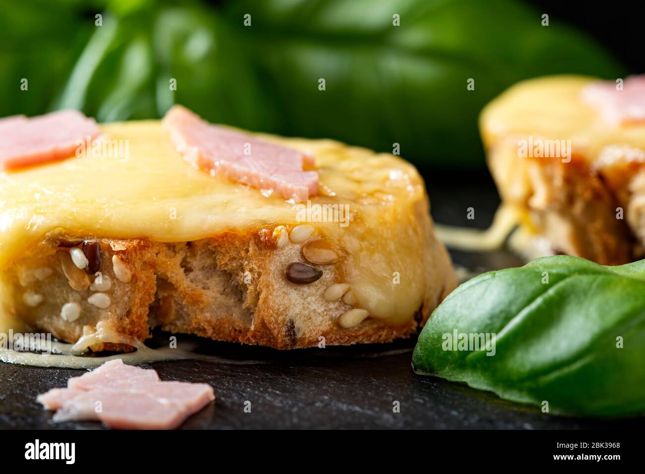 Warm bruschetta with ham, melted cheese and basil Stock Photo
